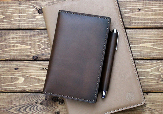 A hand burnished Italian brown leather notebook cover with a pen holder. The cover is crafted with visible hand stitching and has a vintage charm.
