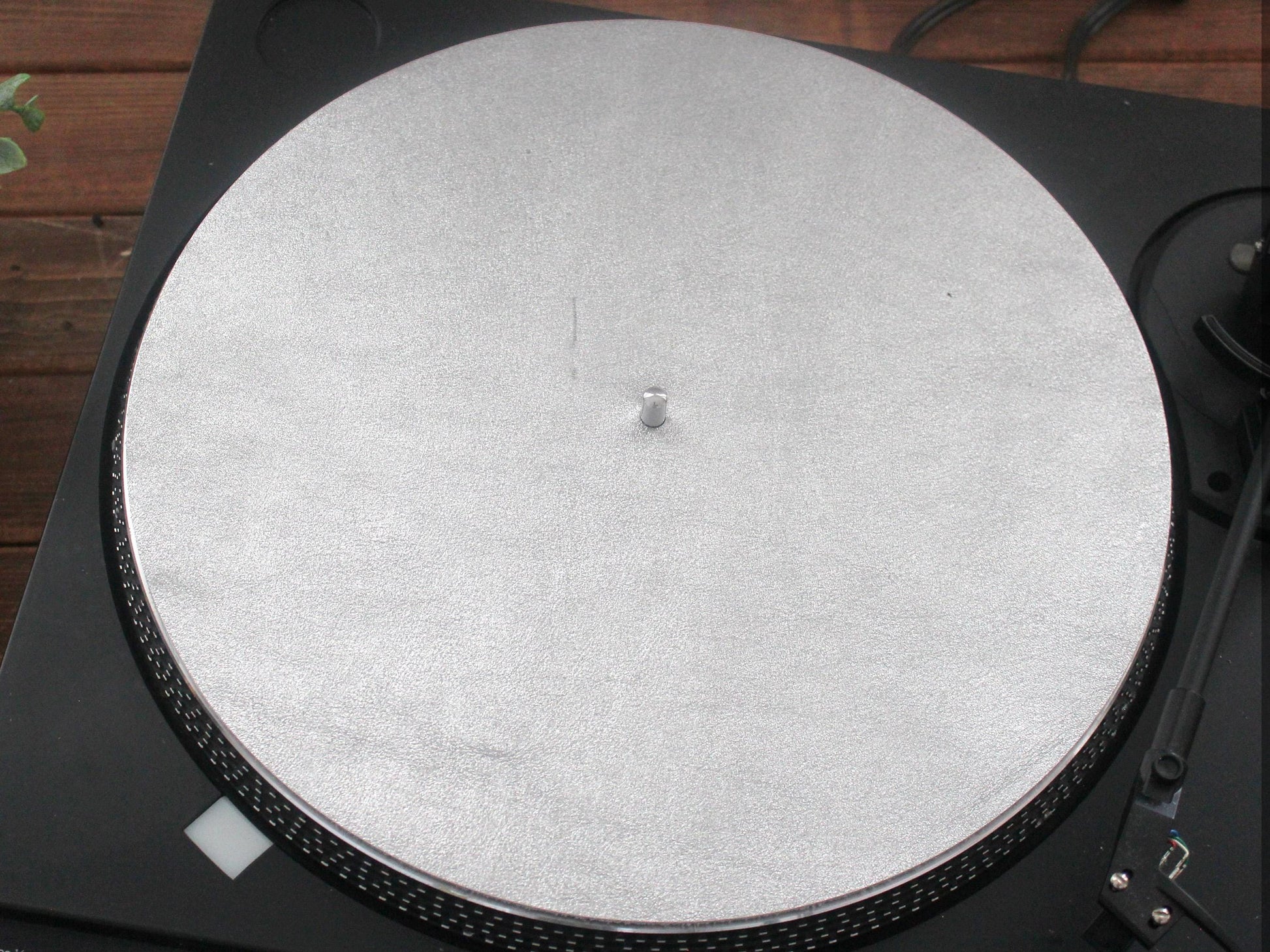 A silver metallic leather turntable platter mat placed on a turntable.