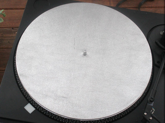 A silver metallic leather turntable platter mat placed on a turntable.