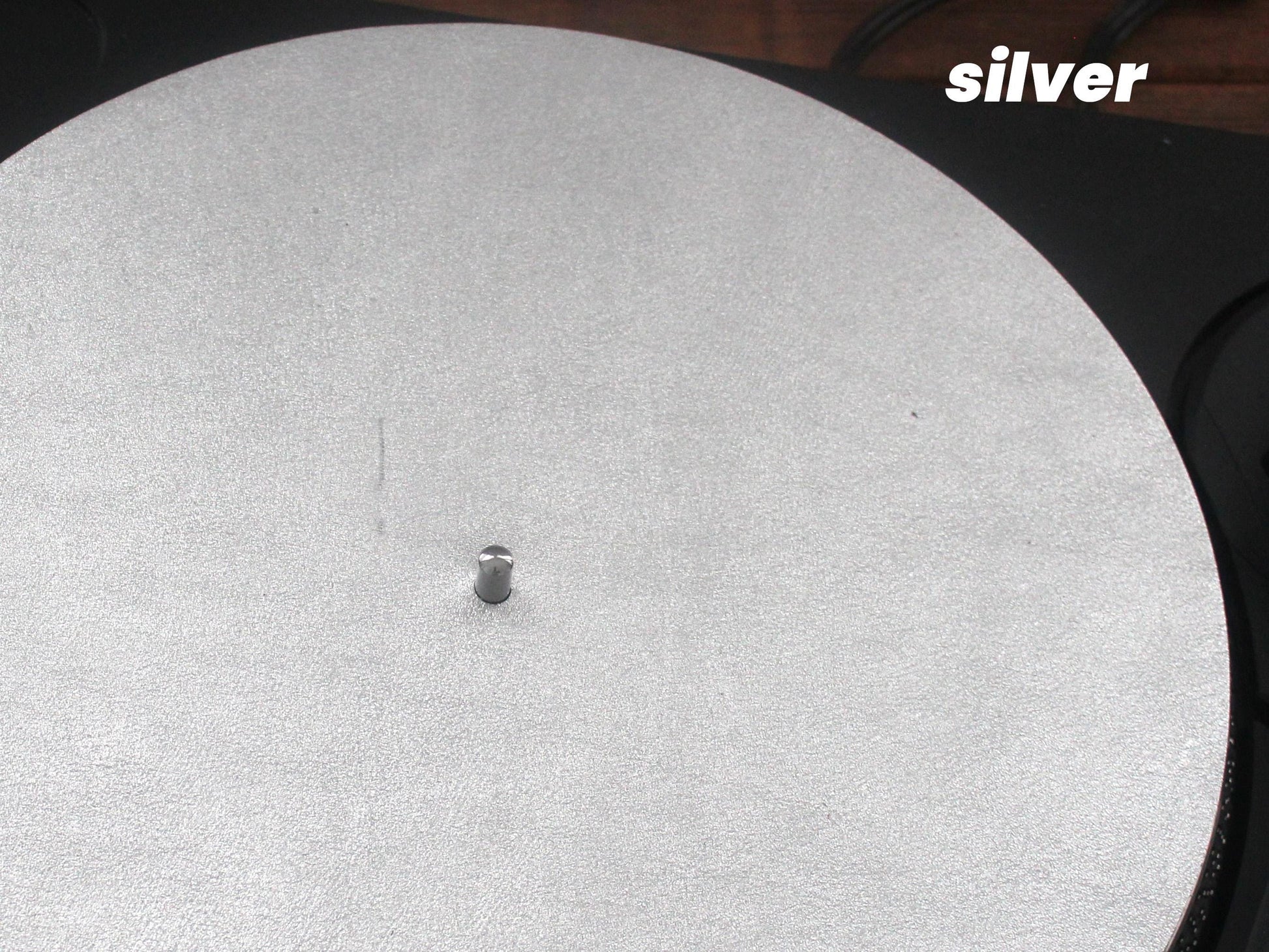 A silver metallic leather turntable platter mat placed on a turntable.