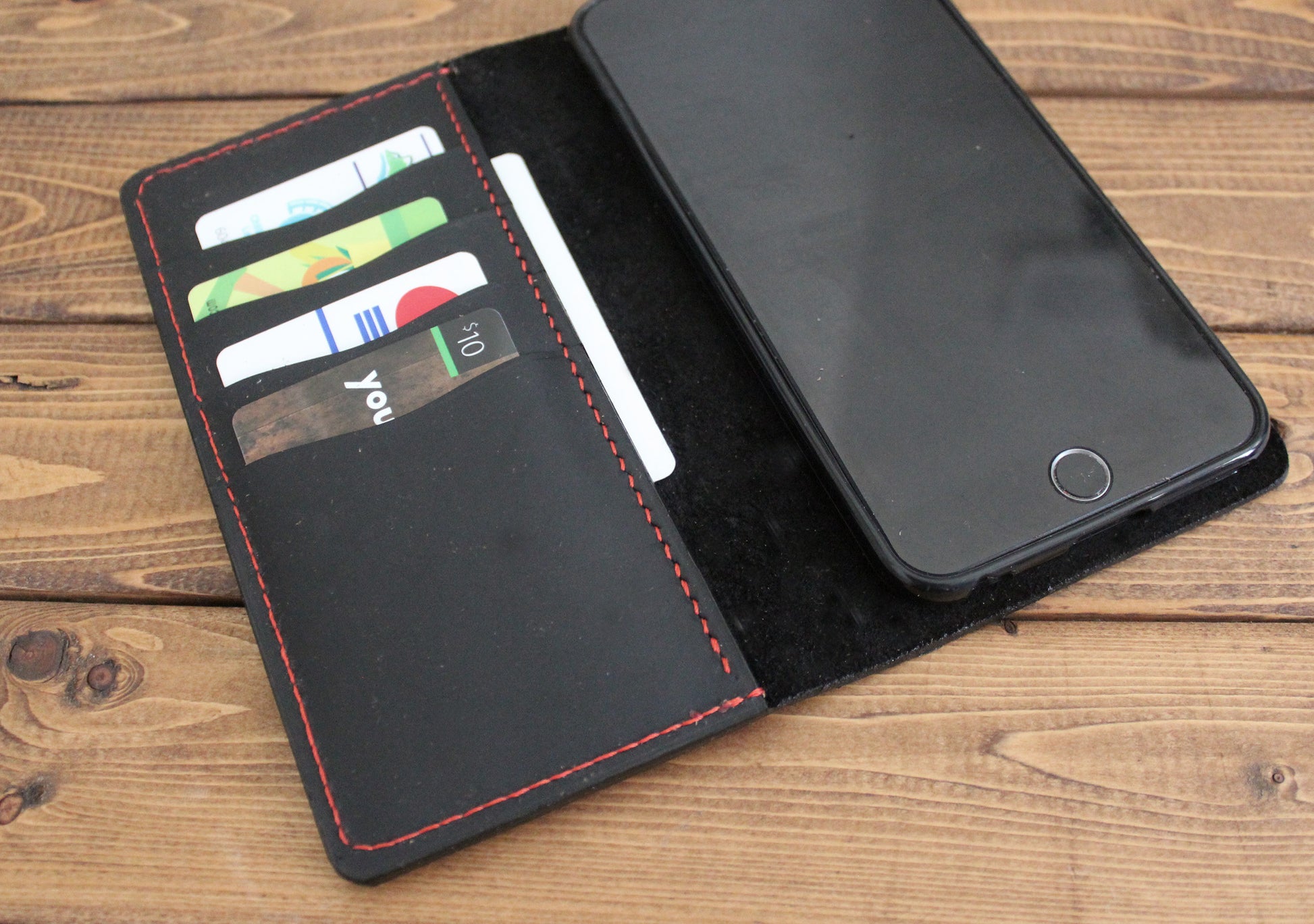 Black iphone leather case with card slots on a wooden surface